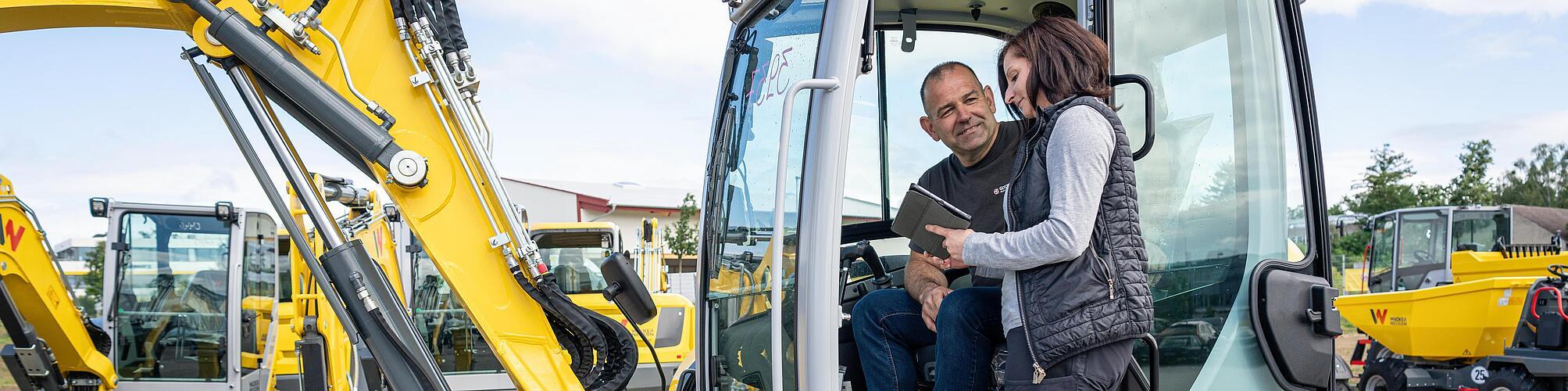 two wacker neuson employees check an excavator