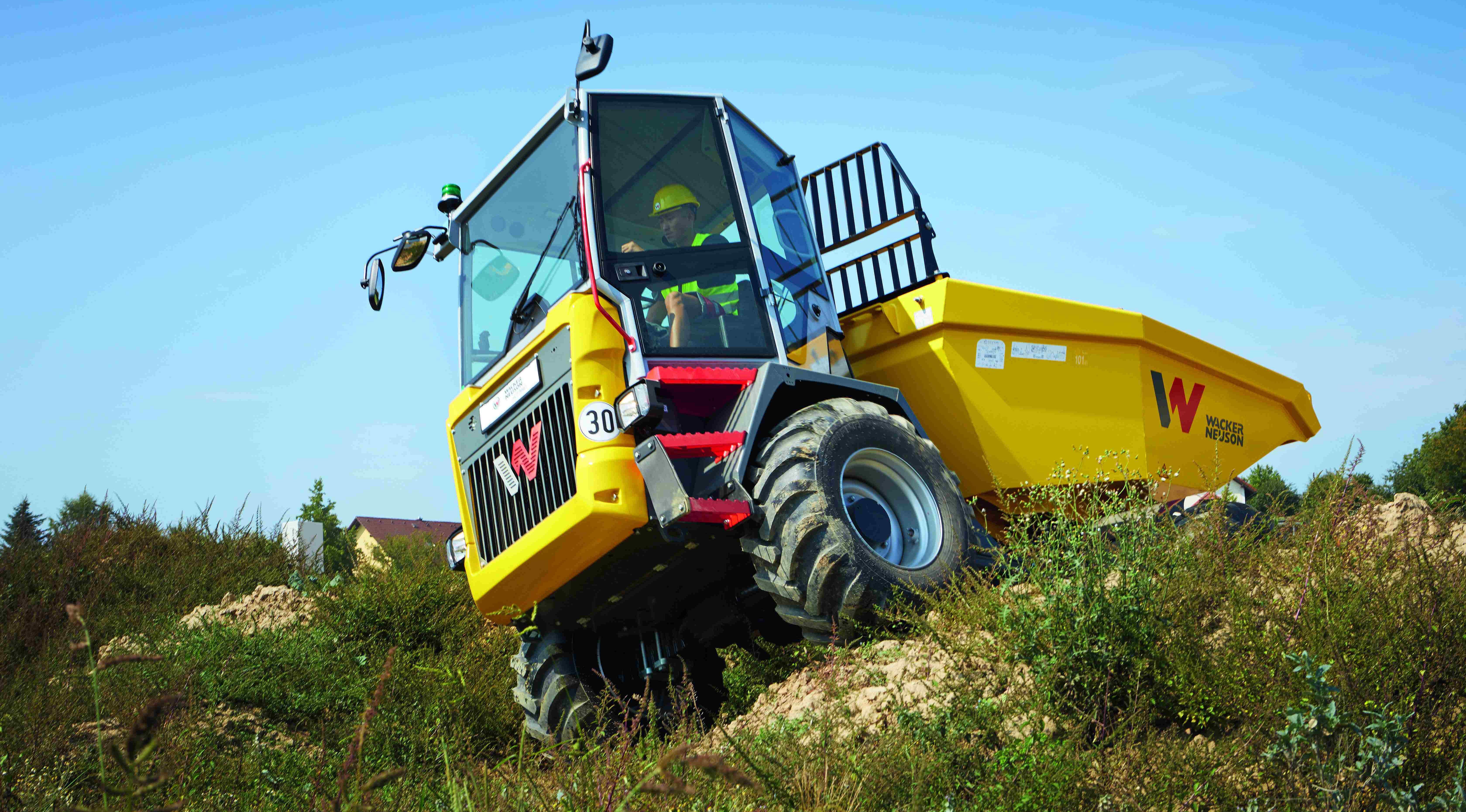 Ein Dumper von Wacker Neuson fährt während Bauarbeiten auf unebenem Gelände, wobei sich der Fahrer in der Kabine befindet