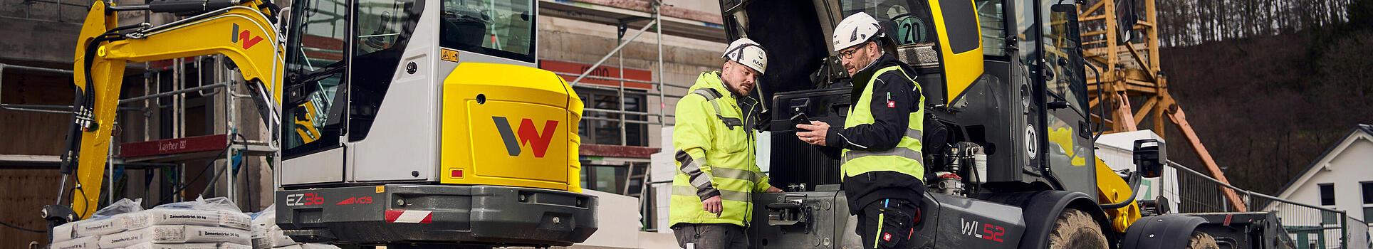 two customers standing in front of wacker neuson machines