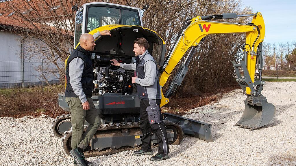 Wacker Neuson employee checking a Wacker Neuson tracked excavator with a customer.