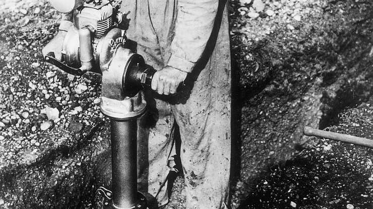 Historic vibratory rammer with combustion engine in application.