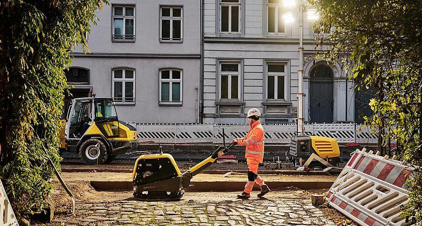 Mann arbeitet an der Straße mit alten, teuren Häusern im Hintergrund