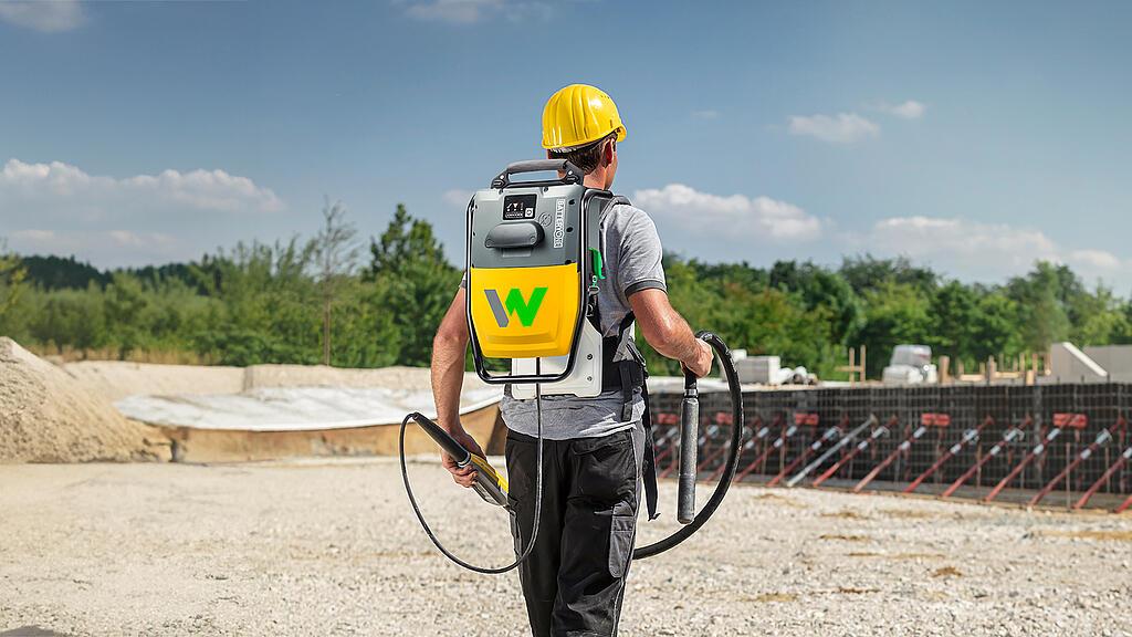 Arbeiter mit einem Rucksack mit internem Vibrator auf einer Baustelle