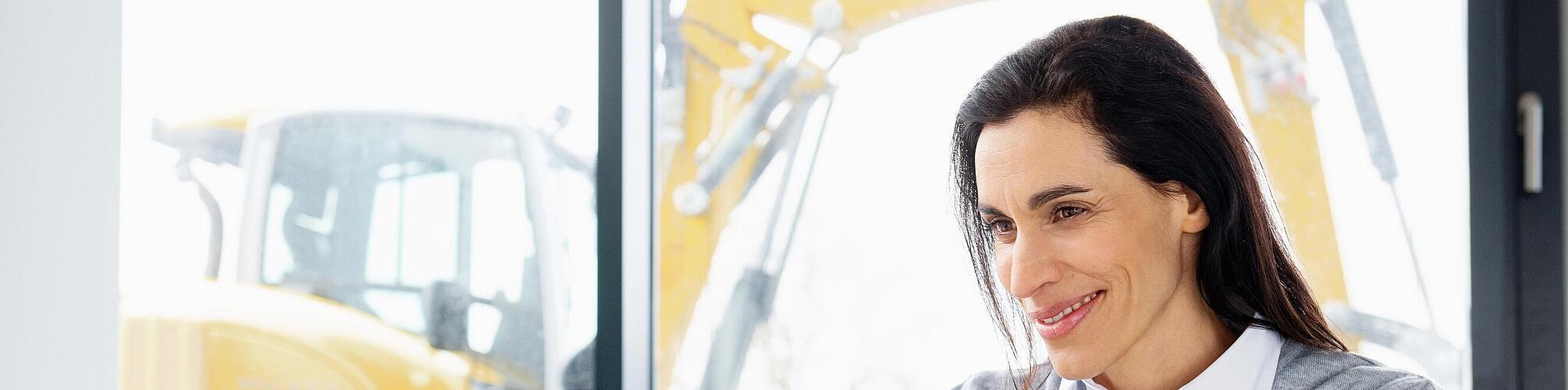 A Wacker Neuson munkatársa mosolyogva ül egy laptop előtt.