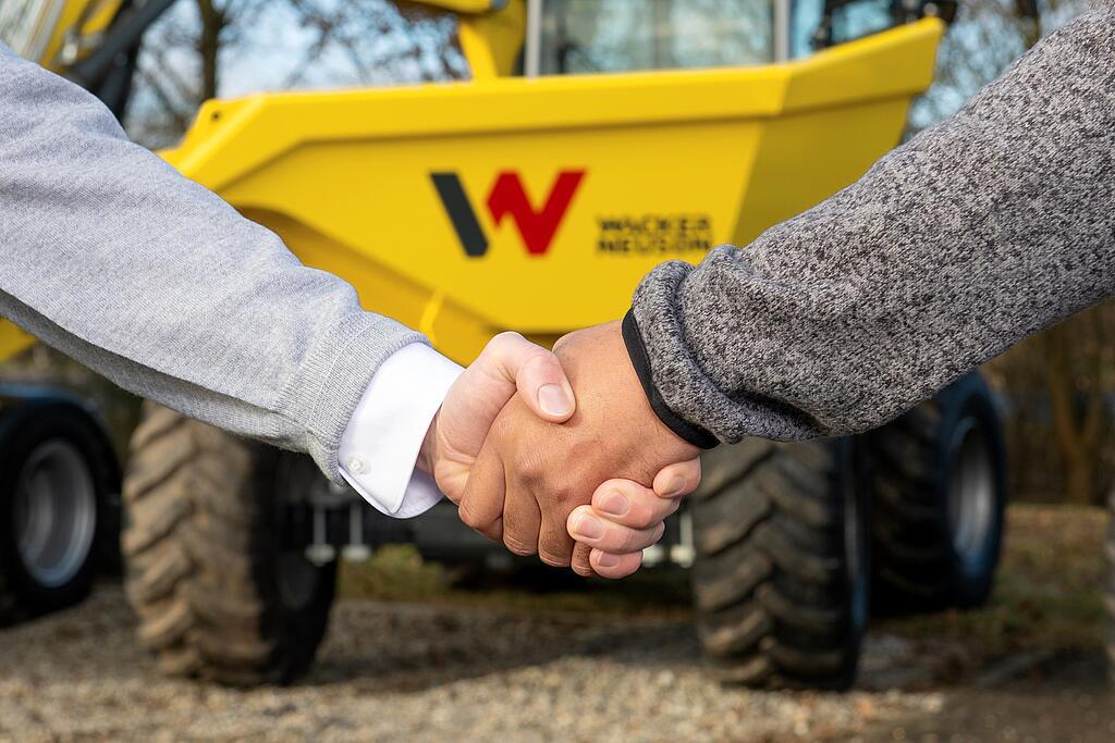 Handshake between Wacker Neuson advisor and customer in front of Wacker Neuson dumper.