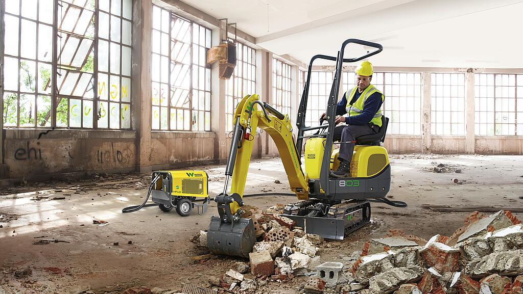 La mini-pelle 803 dual power de Wacker Neuson en utilisation dans un entrepôt.