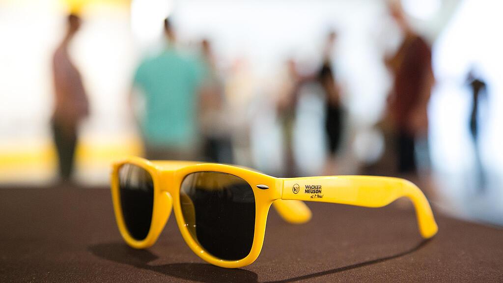 Yellow sunglasses with Wacker Neuson logo.