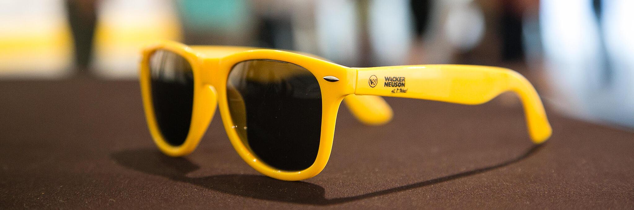 Óculos de sol amarelos com o logotipo da Wacker Neuson.