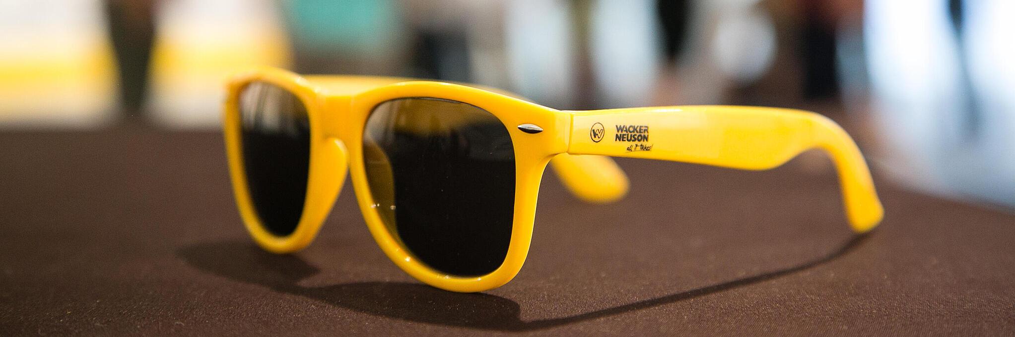 Желтые солнцезащитные очки с логотипом компании Wacker Neuson.
