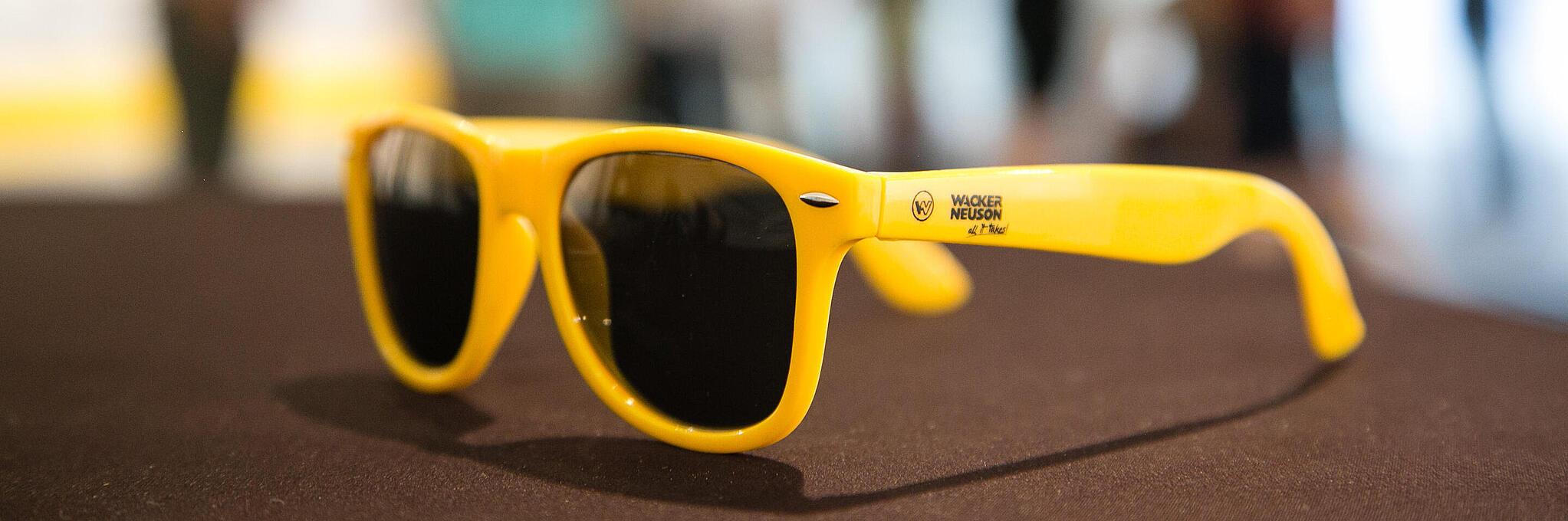 Gelbe Sonnenbrille mit Wacker Neuson Logo.