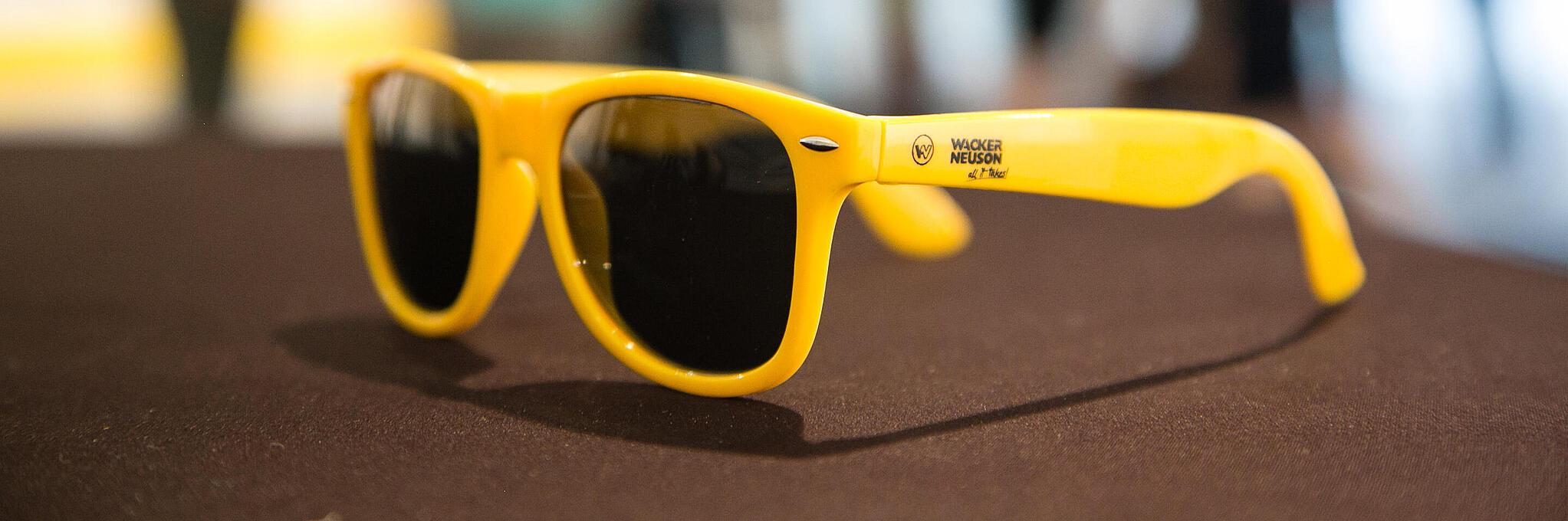 Yellow sunglasses with Wacker Neuson logo.