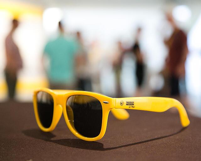 Yellow sunglasses with Wacker Neuson logo.