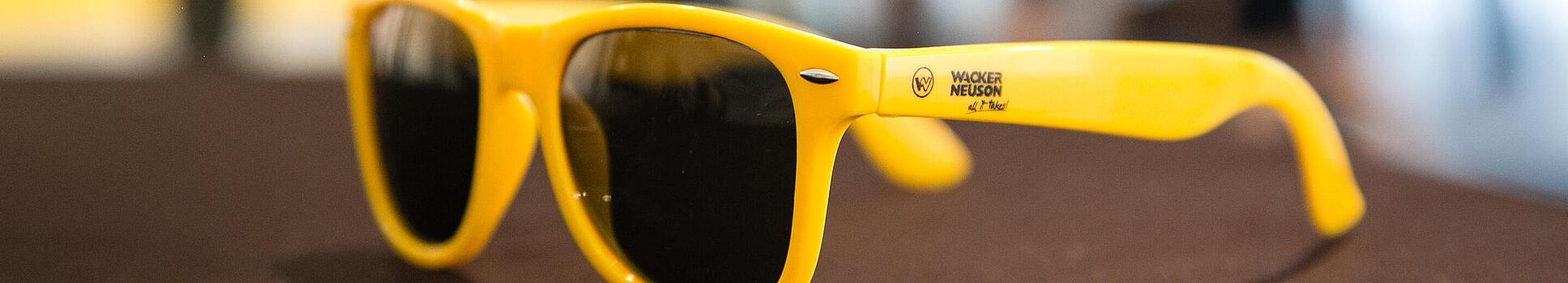 Des lunettes de soleil jaunes portant le logo Wacker Neuson.