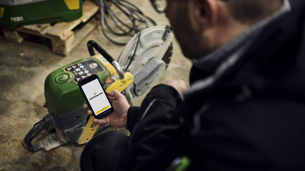 Wacker Neuson employee holding smartphone with construction software EquipCare Pro in his hand.