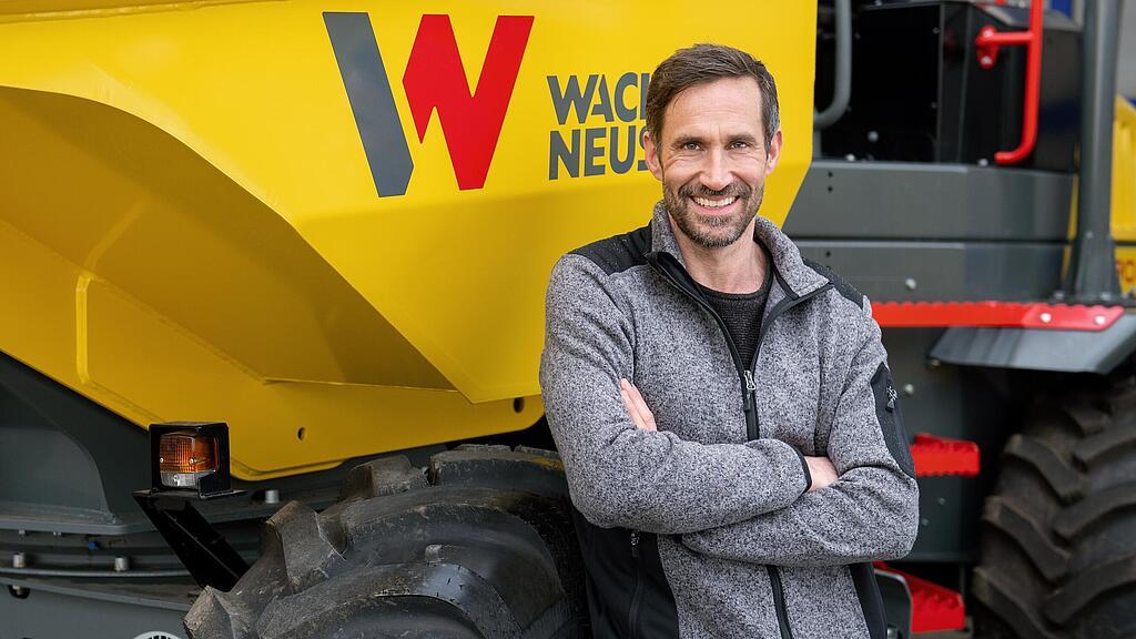 Wacker Neuson customer standing and smiling with arms folded in front of a Wacker Neuson wheel dumper.