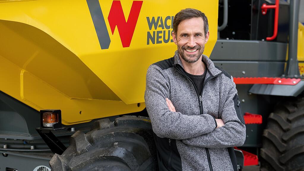 Wacker Neuson customer standing and smiling with arms folded in front of a Wacker Neuson wheel dumper.