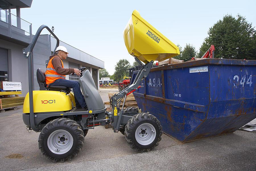 Wheel dumper 1001 unloading with a high-tip skip into a container
