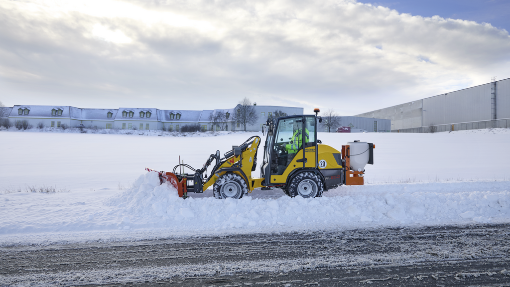 Ein Wacker-Neuson-Radlader räumt Schnee am Straßenrand.