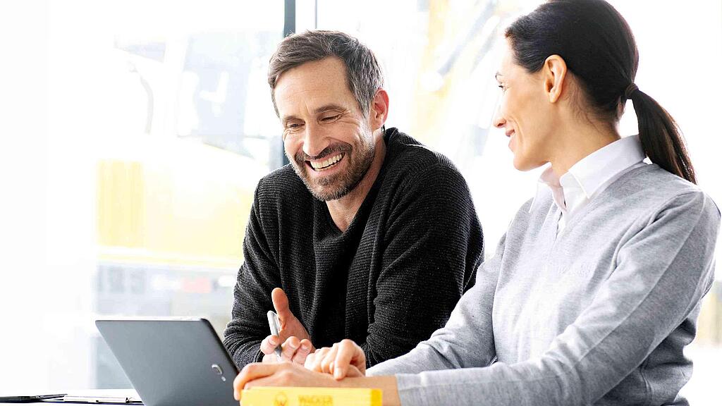 Wacker Neuson customer sitting with Wacker Neuson salesperson in front of a laptop while being advised.