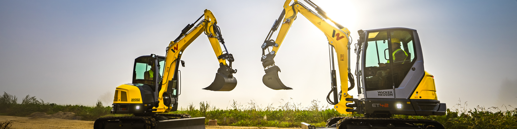 Two Wacker Neuson tracked excavators standing on a construction site.