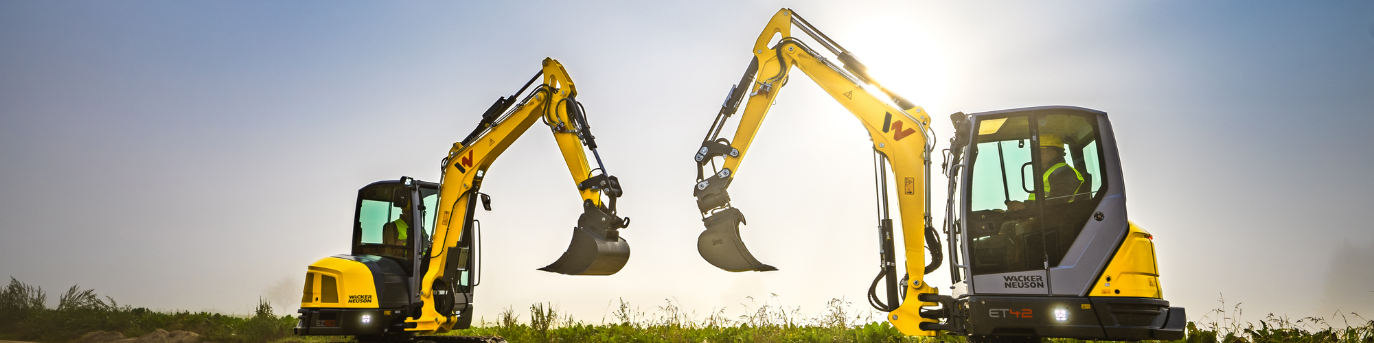 Two Wacker Neuson tracked excavators standing on a construction site.