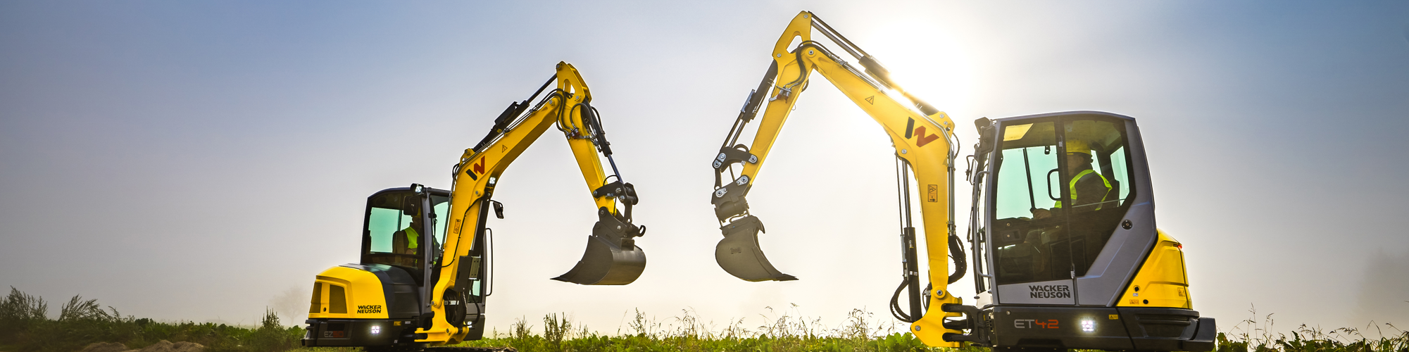 Two Wacker Neuson tracked excavators standing on a construction site.