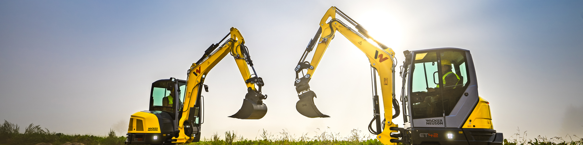 Two Wacker Neuson tracked excavators standing on a construction site.