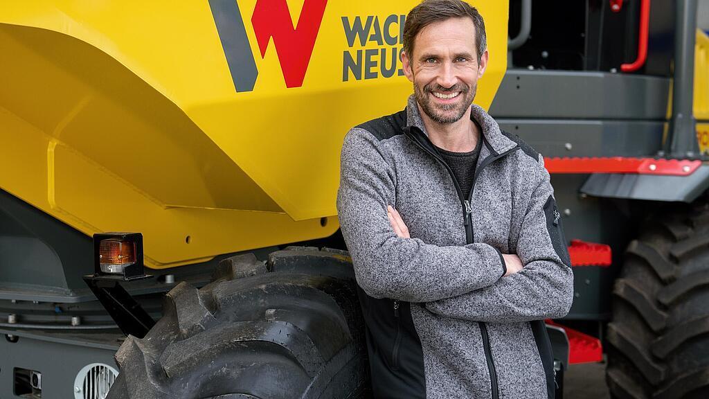 Wacker Neuson customer standing and smiling with arms folded in front of a Wacker Neuson wheel dumper.
